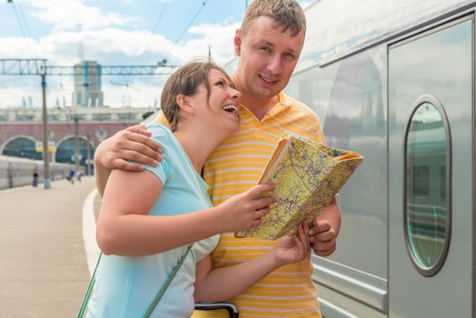 young couple with map in hand near the train at the station