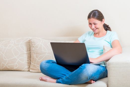 happy girl communicates online while sitting on a sofa