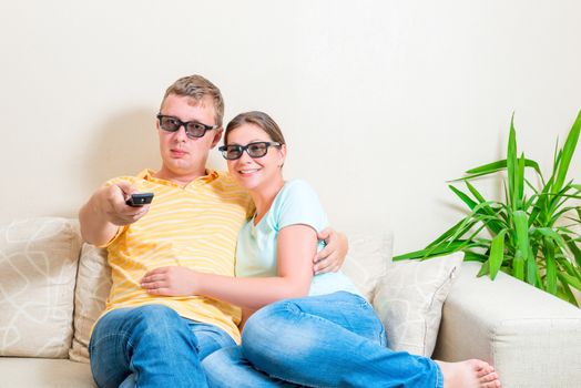 couple watching TV in 3d glasses on the couch in the room