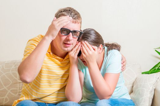 man and woman on the couch watching in 3D glasses scary movie