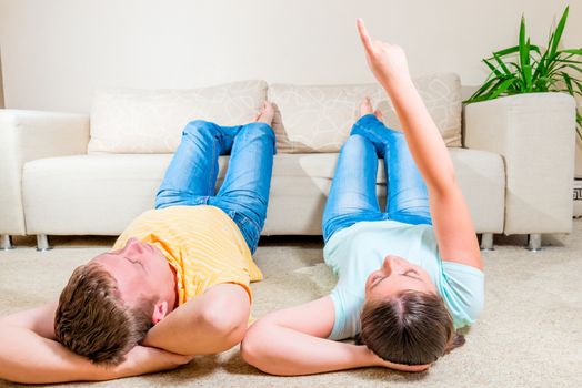 man and woman lie on the floor in the living room near the sofa