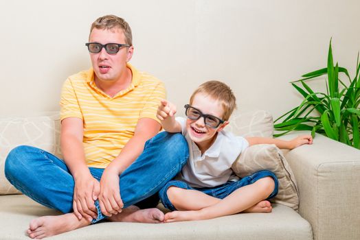 father and son watching a funny movie on TV in 3d glasses