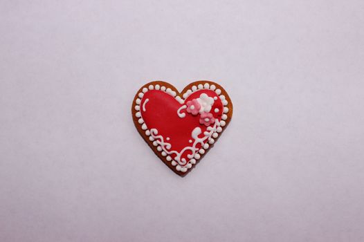 Tastefully ratafia cookie in the form of heart with marzipan flowers on a white background.