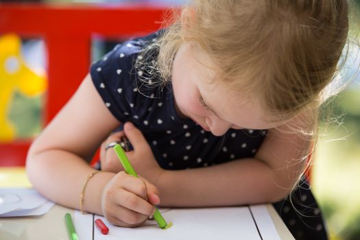 Young blond girl coloring a page with oil pastel crayons