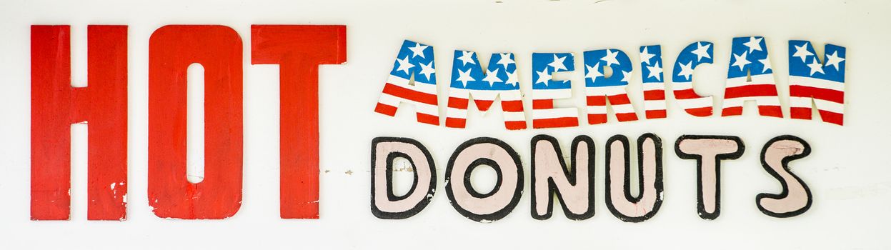 Sign at a Carnival kiosk advertising Hot American Donuts