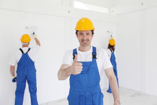 Workman gives thumbs up in front of two painters