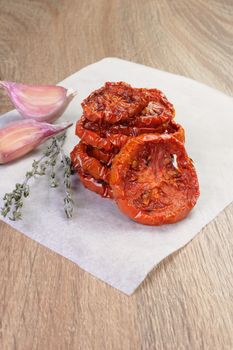 pile of dried tomatoes stacked on a baking paper with cumin and garlic