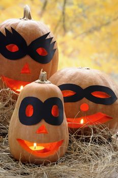 Carved pumpkin illuminated with a black mask in the hay