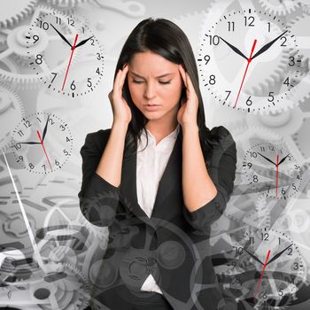 Sad businesswoman looking down on abstract background with clocks