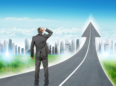 Businessman standing on freeway road going up as an arrow in sky