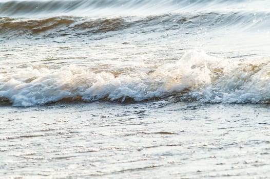 surf on a sandy beach with waves at sunset