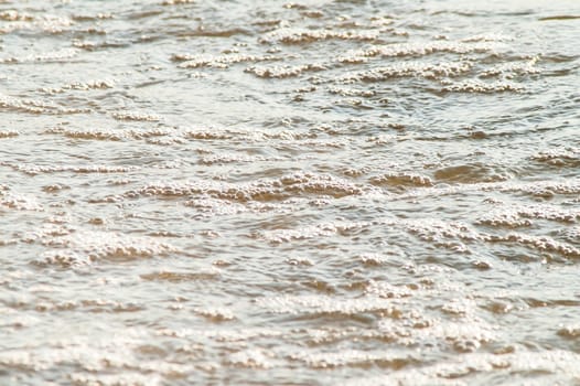 surf on a sandy beach with waves at sunset