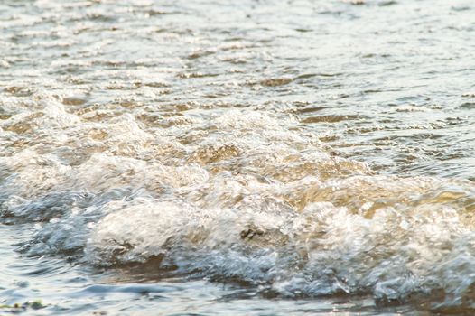 surf on a sandy beach with waves at sunset