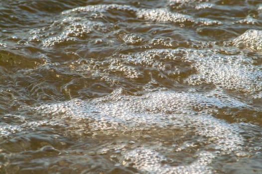 surf on a sandy beach with waves at sunset