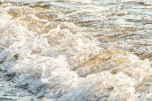 surf on a sandy beach with waves at sunset