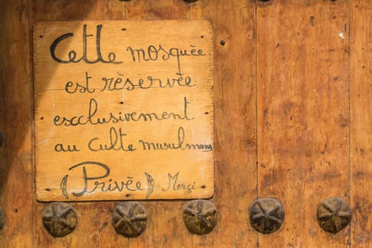 Small board on a gate to a mosque in Marrakesh, informing its reserved just for muslims. Written in French language.