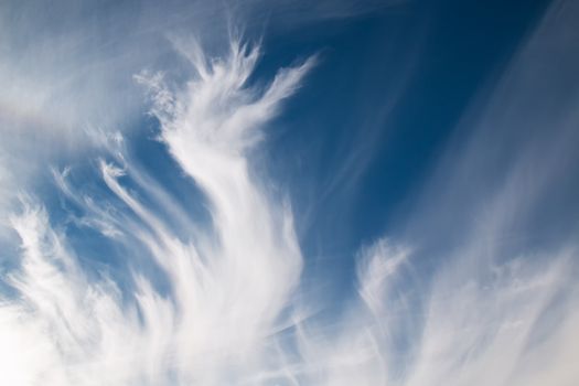 Intense contrast of the white clouds in a shape of flame, on a blue sky.