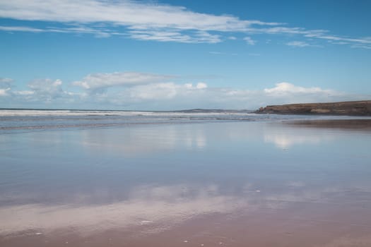 Reflection of a cloudy sky in the wet sand. Mount in the background.