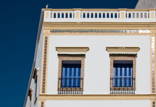 Enlightened corner of a house in Essaouira, Morocco. Matching blue color of the windows shutters and the sky.