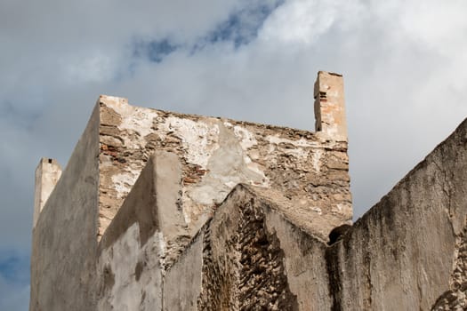 Very old facade of a building in traditional moroccan style, with visible bricks base. Cloudy stormy sky.