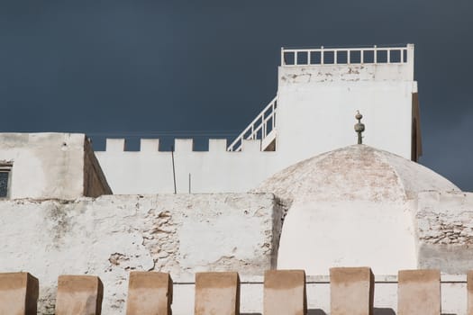 White buildings with an old facade. Stormy sky in the background.