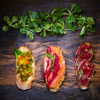 Various bruschettas on wooden table, top view