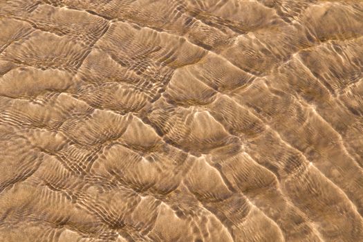 Golden fine sand on the shoreline, creating abstract pattern during the tide.