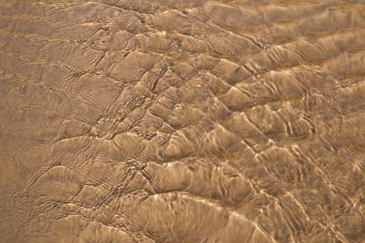 Golden fine sand on the shoreline, creating abstract pattern during the tide.