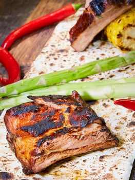 Grilled pork ribs on black cutting board.