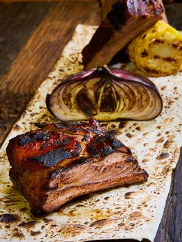 Grilled pork ribs on black cutting board.