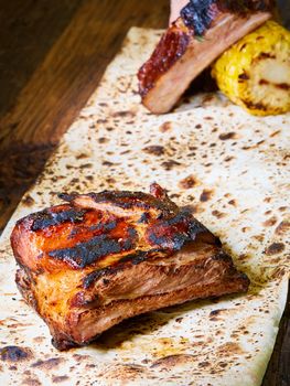 Grilled pork ribs on black cutting board.