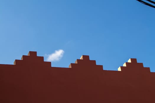 Edge of the fence with traditional decoration. Blue sky with a small cloud in the background.