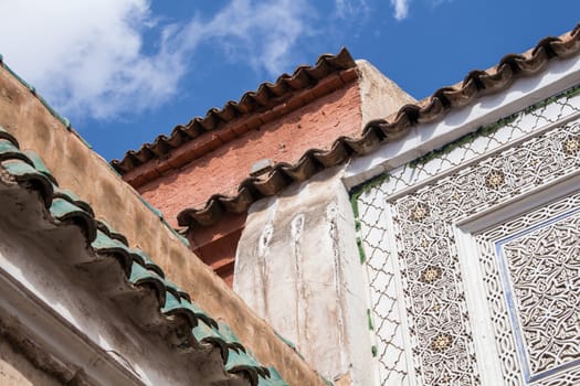 Corner, where are three buildings together. Traditional details, various colors. Blue sky with clouds in the background.