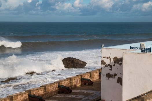 Part of the city fortification wall with many historical cannons. Wild Atlantic ocean and a cloudy sky.