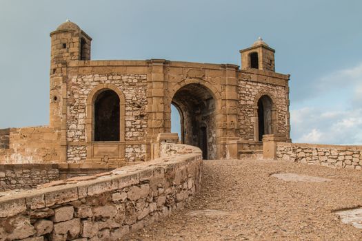 Gate in the city fortification, on the shore of Atlantic ocean in Essaouira. Building made of stones. Cloudy evening sky.