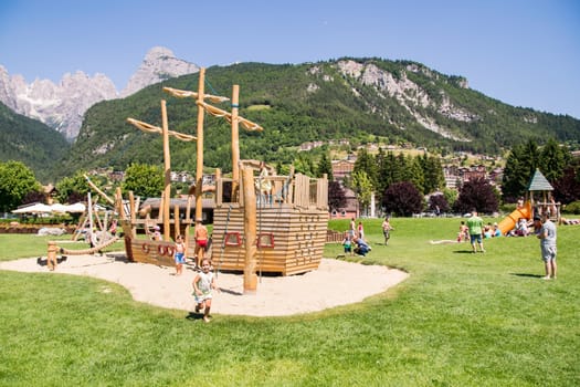 Molveno, Italy - July 10, 2015: Playground structures with natural wood on the banks of Lake Molveno surrounded by the Alps.