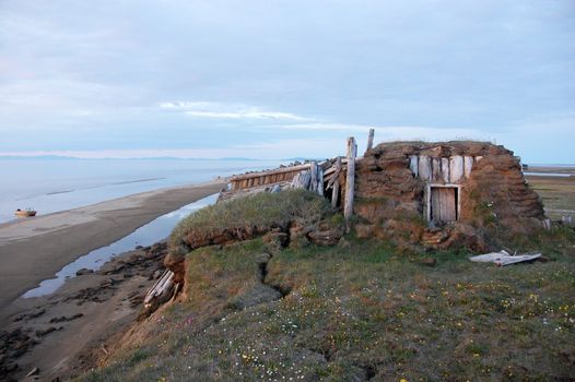 Abandoned broken mud hut at arctic island summer calm sea coast, Chenkul Island, Chukotka, Russia