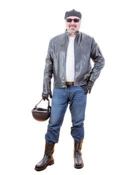 Tough handsome middle aged bearded man in motorcyclist outfit with boots holding helmet as he stands over white background smiling
