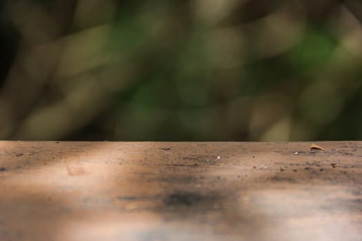 A picture taken in front of the blurred image, Wooden foreground and trees as a backdrop.