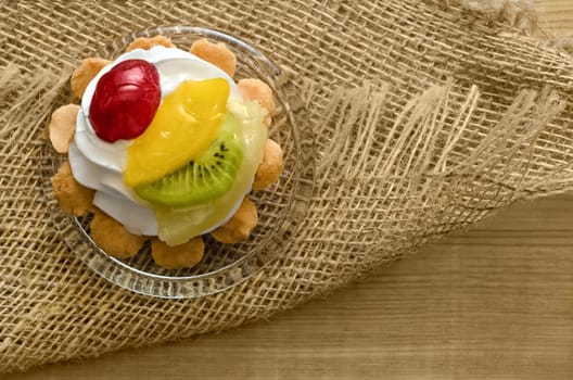 Cake with fruits and cream, on wooden table and burlap