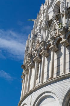 Close up detailed view of Baptisery building in Cathedral Square in Pisa, Italy, on cloudy blue sky background.