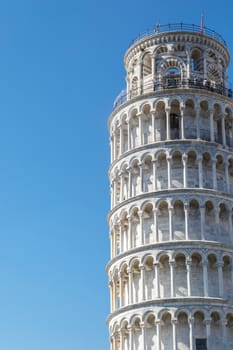 View of historical Pisa Tower in Cathedral Square of Pisa, Italy, on bright blue sky background.