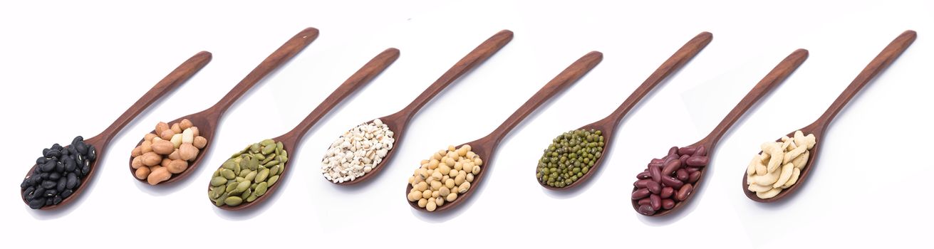 Collection of nuts, seeds in wooden spoon on white background