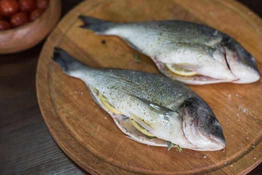 Fresh uncooked dorado with lemon, herbs, oil and spices ready for preparing