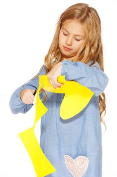 Little cute girl making handmade yellow hearts