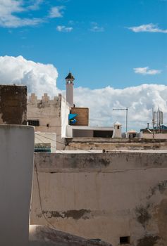 Walls, chimney and roofs of the residential houses in Essaouira, Morocco. Blue sky with white clouds.