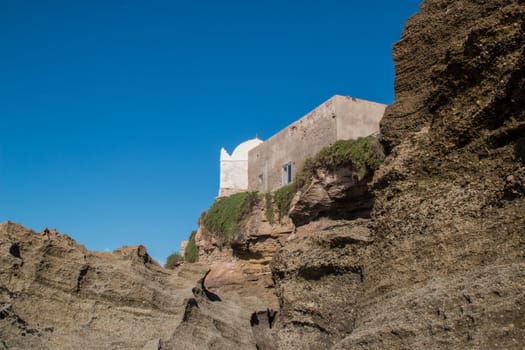 Small mosque in the village on the coast of Atlantic Ocean in Morocco, Moulay Bouzerktoun. Bright blue sky.