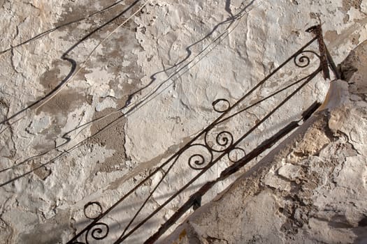 Old wall with damaged painting, creating textures and with shadows of the cables hanging there.