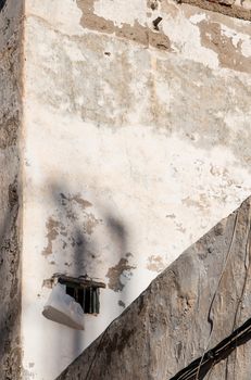 Old wall, enlightened by sun. Damaged facade. Edge of the next wall, which is in the shadow.