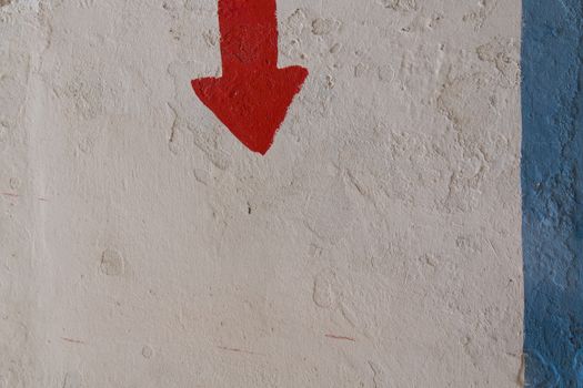 Old structured wall with a blue stripe and red arrow showing the direction down.